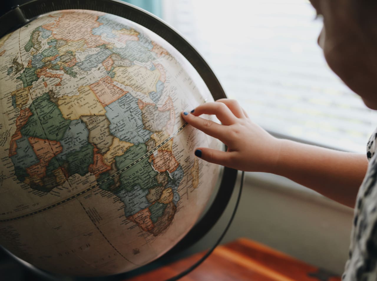 A finger tracing a route across Europe on a globe