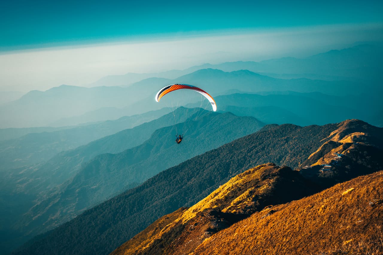 A paraglider over mountain peaks at sunrise